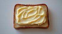 Slice of toasted bread with creamy butter spread on white background, breakfast food concept for healthy morning meal and bakery products.