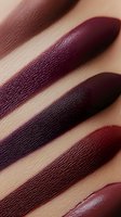 Macro shot of lipstick swatches in deep burgundy, plum and wine shades showing rich texture and pigmentation on skin. Perfect for beauty and cosmetic marketing.