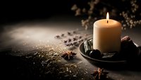 Warm glowing candle surrounded by aromatic spices and herbs creates cozy atmospheric lighting for relaxation, meditation, and home decor ambiance.