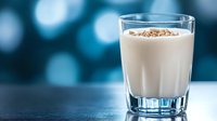 Creamy chocolate milk in clear glass with cocoa powder dusting on blue bokeh background for breakfast beverage concepts and dairy product marketing.