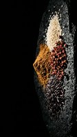 Colorful spices and seeds arranged on dark stone surface with copy space for culinary and cooking projects.