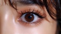 Close-up of brown eye with long eyelashes and wet hair strands. Natural beauty makeup look with dewy skin texture for skincare and cosmetics concepts.