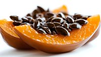 Fresh pumpkin slice with dark seeds on white background, showcasing vibrant orange flesh and contrasting black seeds for cooking or seasonal recipes.