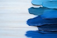 Blue paint brush strokes gradient from light to dark shades on white wooden background, creating artistic texture and abstract composition for creative design projects.