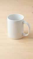 White ceramic coffee mug on wooden table surface ready for custom printing and branding applications.