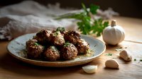 Homemade beef meatballs with herbs on rustic ceramic plate, served with fresh garlic and parsley on wooden cutting board, moody lighting.