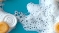 Foamy soap bubbles and bath products on turquoise background for hygiene and cleansing concepts in spa wellness advertising materials.