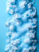 White foam bubbles flowing on bright blue background creating abstract cleaning and freshness concept for hygiene products and spa treatments.
