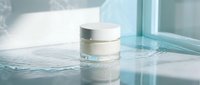 Luxury skincare cream jar on wet surface with water droplets and soft natural lighting for beauty and cosmetics advertising.