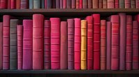 Row of vintage books in shades of red and pink on wooden library shelf, creating harmonious color gradient pattern for literature and education concepts.