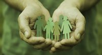Protective hands holding green paper family cutouts symbolizing care, support and family protection concepts for insurance and social services.