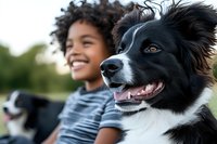 Happy African American child with curly hair enjoying outdoor time with friendly black and white Border Collie dog in natural park setting during golden hour.