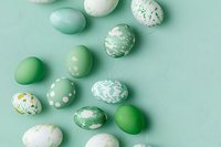 Decorated Easter eggs in mint green and white tones scattered on pastel background. Modern minimal holiday composition with painted eggs creates fresh spring mood.