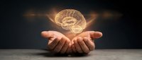 Glowing golden brain floating above open cupped hands against dark background representing mental health, psychology, neuroscience and cognitive thinking concepts.