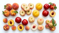 Assorted fresh apples and peaches with leaves arranged on white background, including red, yellow, and cream varieties, some cut in half showing pits and flesh for food styling and culinary use.
