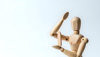 Wooden artist mannequin figure in dynamic pose with raised arm against clean white background for creative design projects.