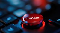 Red glowing cancel button on black keyboard with dramatic lighting and bokeh effect in background, close-up macro photography for business concepts.