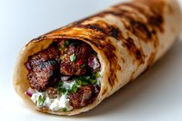 Grilled beef shawarma wrap with tender meat chunks, fresh herbs, red onions and creamy white sauce, rolled in charred flatbread. Perfect for menu photography.