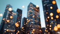 Modern cityscape with glowing bokeh lights in foreground creating dreamy urban atmosphere at dusk, skyscrapers silhouetted against blue evening sky.