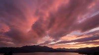 Dramatic pink and purple sunset sky with swirling clouds over mountain silhouettes creating stunning natural landscape scenery for backgrounds and travel content.