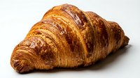 Freshly baked croissant with golden, flaky layers and crispy exterior on white background. Suitable for bakery, food, and culinary content.