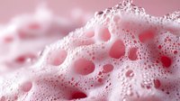 Pink soap foam macro shot with bubbles and soft texture creating abstract pattern with delicate light and shadow play. Suitable for cosmetic and hygiene concepts.