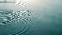 Concentric water ripples spreading across calm blue-green surface creating peaceful zen meditation atmosphere for wellness spa relaxation mindfulness concepts.