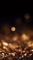 Golden bokeh lights on dark background with glowing circular orbs floating above sparkling surface, creating magical atmospheric effect for festive designs.