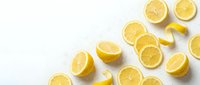 Fresh sliced lemons with water drops scattered on a white background, showcasing vibrant yellow citrus fruit for food and beverage design.