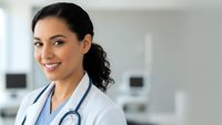 Smiling female doctor with stethoscope in modern hospital setting. Professional healthcare worker portrait for medical and wellness content.