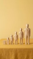 Wooden figurines arranged by size on yellow fabric, symbolizing human growth stages from infant to adult against a warm background.
