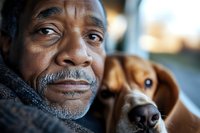 Elderly African American man with gray beard embracing loyal brown dog companion in warm indoor setting showcasing unconditional love and friendship.