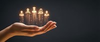 Glowing light bulb figures floating above open palm against dark background, representing ideas, teamwork, innovation, and human resources management.