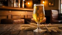 Golden beer in elegant glass with wheat stalks on rustic wooden table in warm pub atmosphere for brewery marketing and hospitality industry.