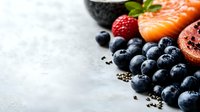 Fresh blueberries, raw salmon fillet, and red berries arranged on gray concrete background with copy space, healthy superfood ingredients for cooking.