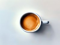 Fresh espresso coffee in white ceramic cup with rich crema foam viewed from above on clean white background for cafe menu design.