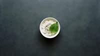 Creamy white sauce or dip in ceramic bowl with fresh green herb garnish on dark slate background for culinary presentations.