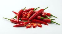 Fresh red chili peppers pile with green stems on white background, spicy hot cooking ingredient for culinary recipes and food preparation isolated.