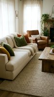 Cozy modern living room interior with beige sofa, leather armchair, wooden coffee table, green pillows, natural light from large windows and plants.