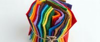 Colorful rainbow felt fabric sheets stacked and tied with natural twine rope for crafting projects and DIY textile arts on white background.