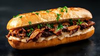 Gourmet submarine sandwich with caramelized onions, melted cheese and fresh herbs on crusty bread roll against dark background for restaurant menu design.