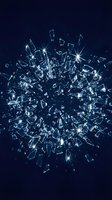 Shattered glass explosion with sparkling fragments and bright light rays on dark blue background for dramatic impact design concepts.