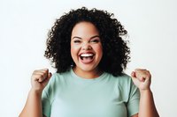 Excited young African American woman with curly hair celebrating success with raised fists, wearing mint green t-shirt on white background.