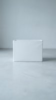 Minimalist white rectangular storage box on a light gray concrete floor, clean modern design for home organization and product mockup concepts.