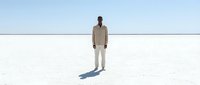 Man in beige jacket and light pants standing alone on vast white salt flat under clear sky, minimalist composition for conceptual and editorial use.