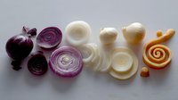 Fresh sliced onion varieties arranged in gradient color from deep purple to golden, showing cross sections and spiral cuts on white background for food photography.