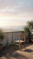 Wooden chair on rooftop terrace with olive plants and misty mountain landscape at sunrise, ideal for lifestyle and interior design projects.