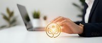 Businessman holding glowing light bulb icon above desk with laptop, representing innovation, creative ideas, and sustainable business solutions for corporate success.