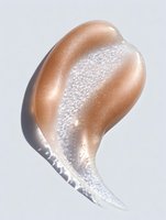 Golden bronze makeup foundation smear with shimmer particles on white background. Cosmetic texture swatch for beauty and skincare advertising campaigns.