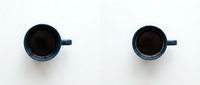 Two blue ceramic coffee mugs filled with black coffee viewed from above on white background, minimalist flat lay composition for morning beverage concepts.